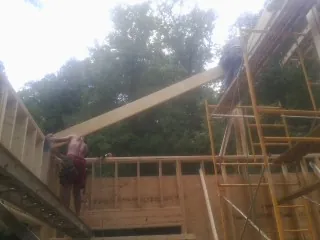 Carpenter raising a rafter beam on a new second story frame in Markesan