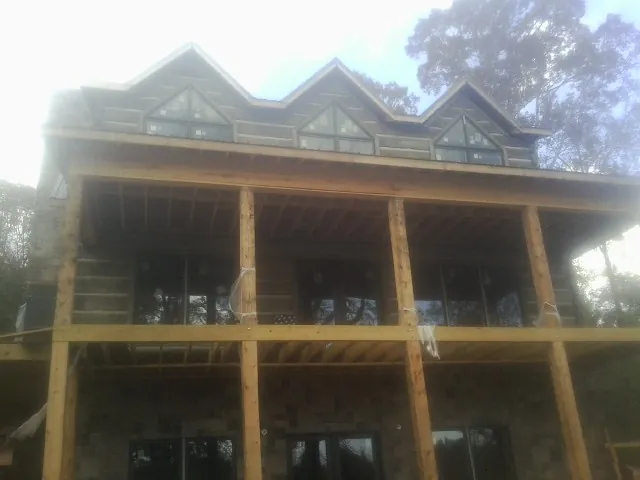 Dormers and porch framing on a large log home under construction — Roof Coating work by our crew in Markesan