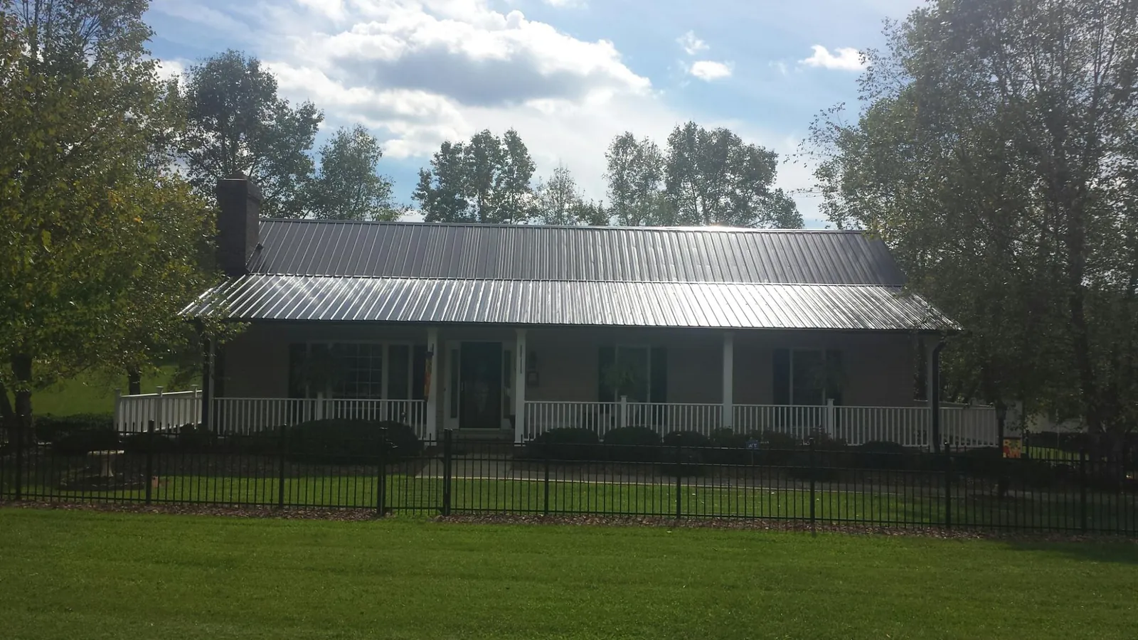 Gray metal roof on a brick ranch with a full width front porch — Gutter Guard Installation work by our crew in Markesan
