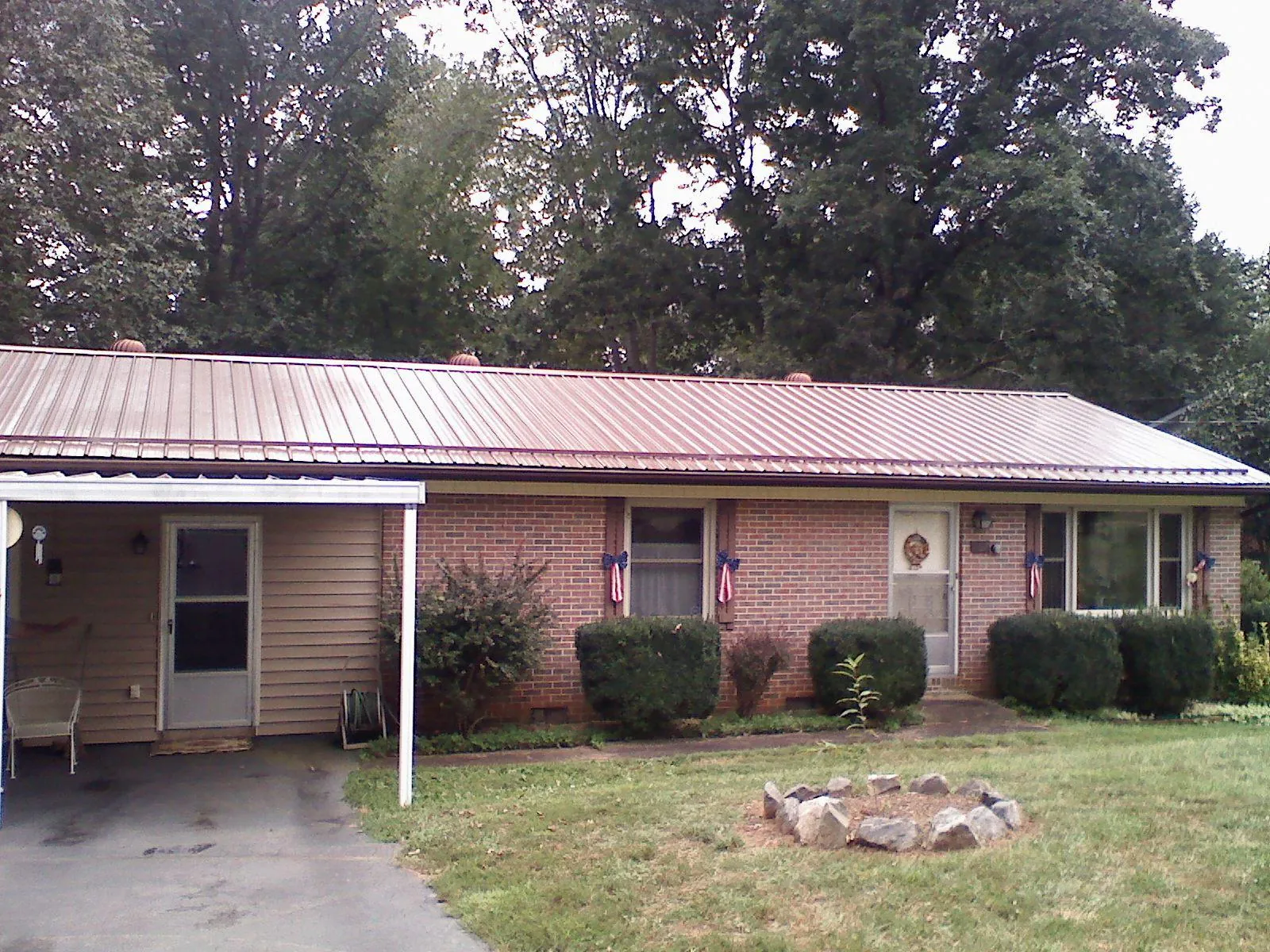 Bronze metal roof and carport on a brick ranch home — Roof Repair work by our crew in Markesan