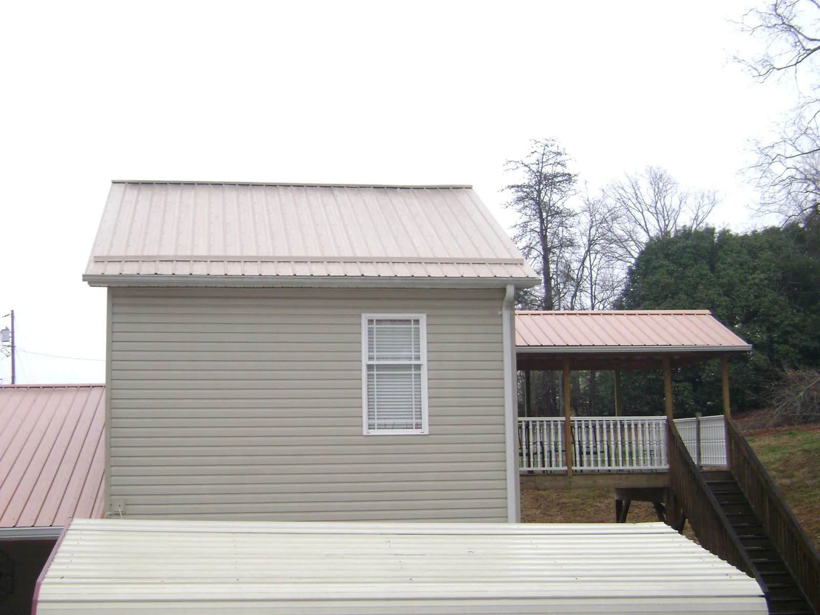 Tan metal roofs on a two story addition and attached porch, from a Roof Replacement job in Markesan